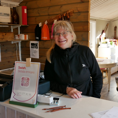 Ingrid står bakom en disk i sin reception och ler.