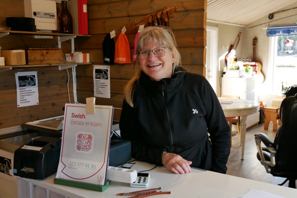 Ingrid står bakom en disk i sin reception och ler.