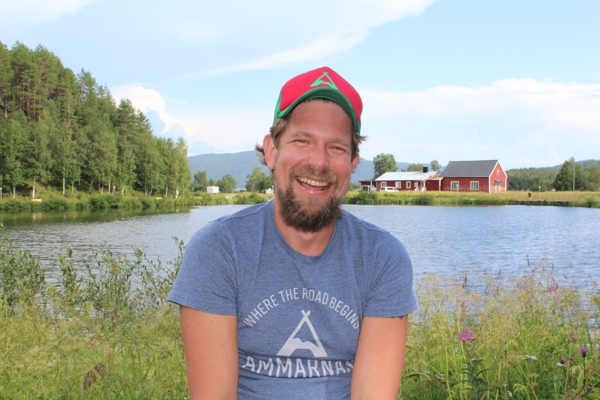 Marcus Eriksson sitter framför en sjö och ett rött hus