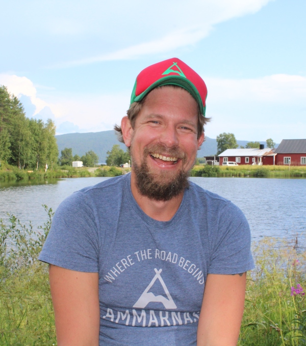 Marcus Eriksson sitter framför en sjö och ett rött hus