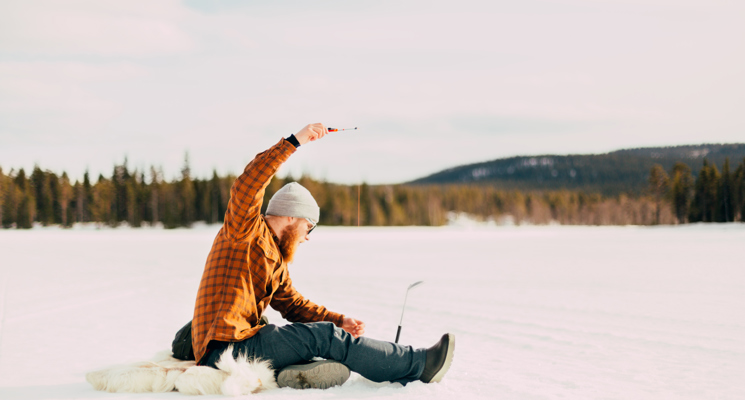 En man sitter och fiskar på isen