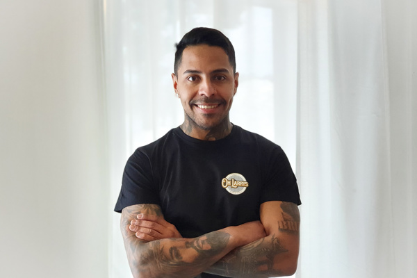 En man som har t-shirt med texten Oh Larrys! och tatuerade underarmar.