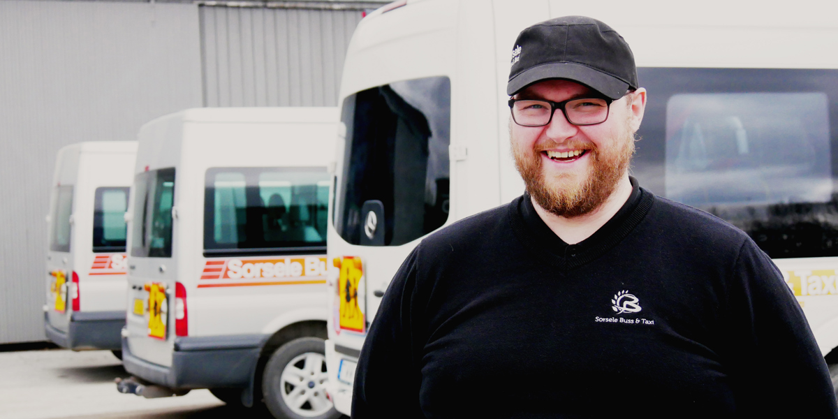 Oscar Öjeryd står och ler framför tre parkerade minibussar.