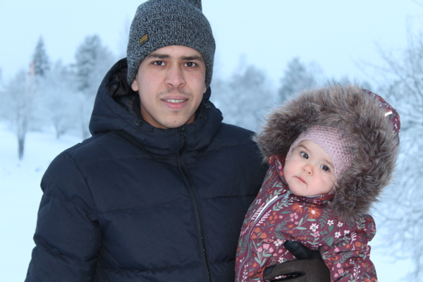 En man står med en flicka i famnen, det är vinter ute.