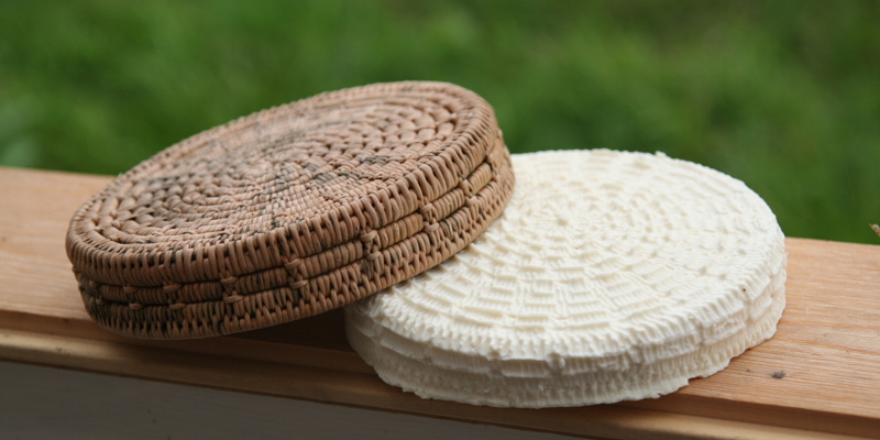 Fotografi av en kaffeost och en ostkorg som ligger på en fönsterkarm. Utanför syns en suddig gräsmatta.