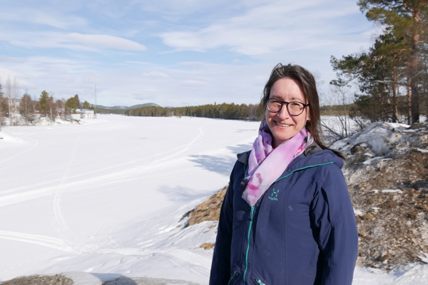 En kvinna står framför den frusna Vindelälven.