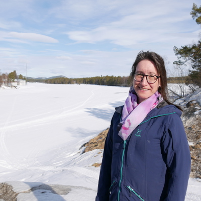 En kvinna står framför den frusna Vindelälven.