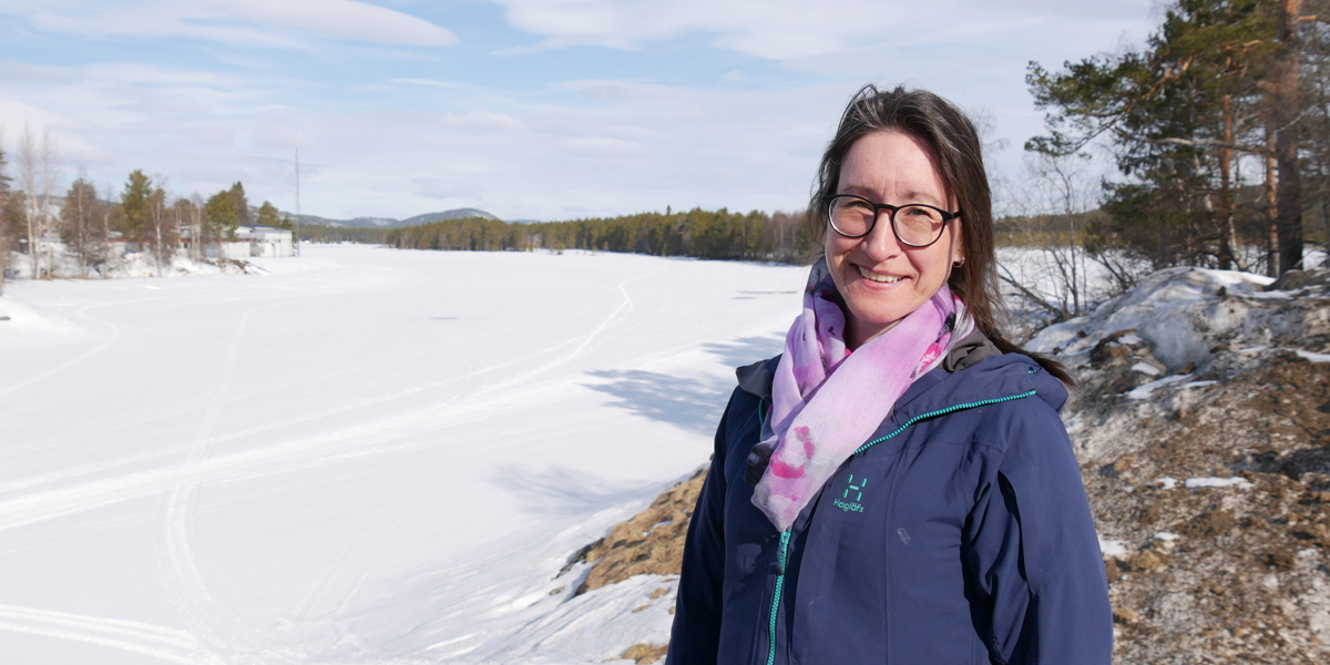 En kvinna står framför den frusna Vindelälven.