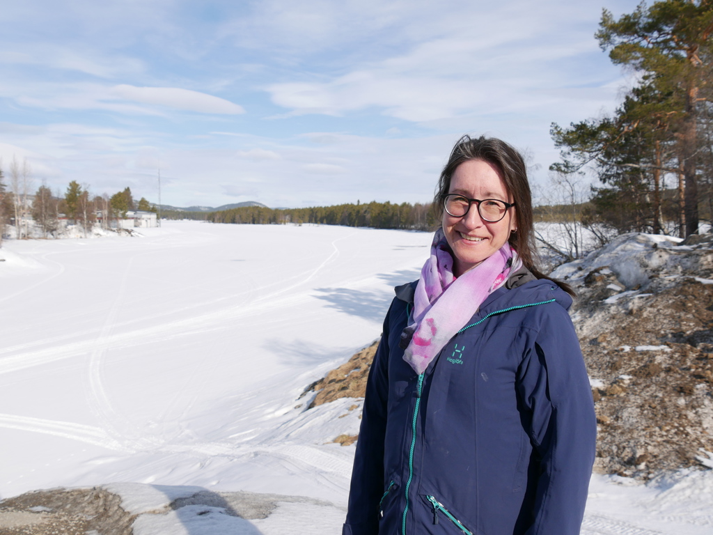 En kvinna står framför den frusna Vindelälven.